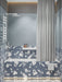 Badezimmer mit Melodie Rock Terrazzo Blau 60 × 60 cm Feinsteinzeug-Wand- und Bodenfliesen mit sanft blauer Basis und großen weißen Zuschlägen, kombiniert mit strukturierten blauen Wandfliesen, weißen Armaturen und weicher, indirekter Beleuchtung.
