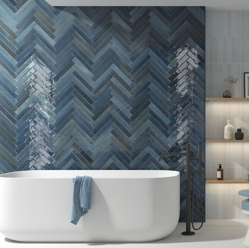 Modernes Badezimmer mit Lisbon Blue Green Wandfliesen aus Feinsteinzeug im handwerklichen Stil im Format 5 × 30 cm, im Fischgrätmuster verlegt, um eine ausdrucksstarke Akzentwand zu schaffen. Kombiniert mit einer freistehenden Badewanne, schwarzen Armaturen und sanften blauen Akzenten entsteht ein luxuriöses, spa-inspiriertes Interior.