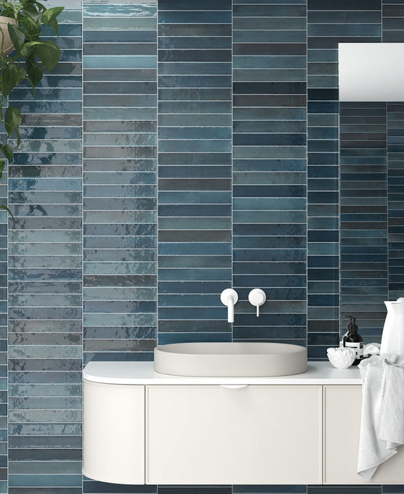 Modernes Badezimmer mit Lisbon Blue Green Wandfliesen aus Feinsteinzeug im handwerklichen Stil im Format 5 × 30 cm, horizontal verlegt, um eine ausdrucksstarke blau-grüne Akzentwand zu schaffen. Kombiniert mit einem schwebenden Waschtischunterschrank, weißen Armaturen und modernem Styling entsteht ein beruhigendes und zugleich elegantes Interior.
