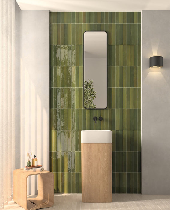 Modernes Badezimmer mit Lisbon Olive Green Wandfliesen aus Feinsteinzeug im handwerklichen Stil im Format 5 × 30 cm, vertikal verlegt, um eine markante Akzentwand zu schaffen. Kombiniert mit einem Waschtischunterschrank aus hellem Holz, schwarzen Armaturen und sanften neutralen Farbtönen entsteht ein modernes, natürlich inspiriertes Interior.