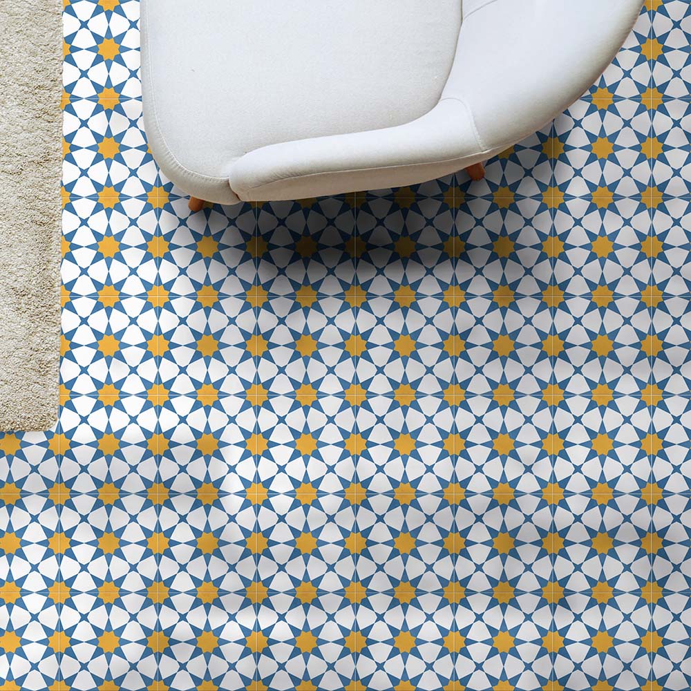 Wohnzimmergestaltung mit Agadir Blau & Gelb Fliesen im marokkanischen Stil im Format 20 × 20 cm aus Feinsteinzeug, verlegt als Bodenbelag mit geometrischem Sternmuster in Blau, Weiß und warmem Gelb. In Kombination mit einem modernen Sofa entsteht eine helle, einladende Raumwirkung.