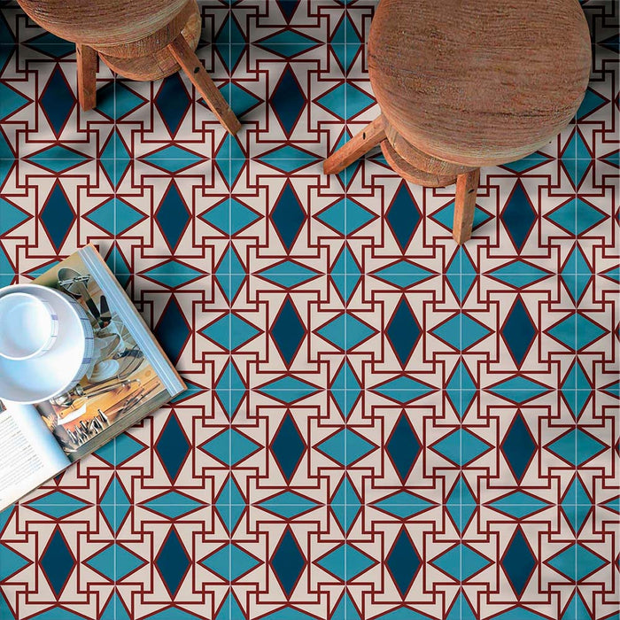 Innenboden gestaltet mit Abstrakter Iris Musterfliese im Format 20 × 20 cm, mit einem ausdrucksstarken geometrischen Design in tiefem Blau, Petrol und sanften Cremetönen, ergänzt durch feine rote Details. Das sich wiederholende Muster sorgt für eine markante, dekorative Optik und wird mit Holzschemeln und Accessoires in Szene gesetzt, um die Fliesen als ausdrucksstarken Bodenbelag für Küchen, Essbereiche oder Akzentzonen zu präsentieren.