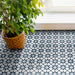 Wohnbereich mit Agadir Blau Fliesen im marokkanischen Stil im Format 20 × 20 cm aus Feinsteinzeug, verlegt als Bodenbelag mit geometrischem Sternmuster in Blau und Weiß. Natürliches Licht und eine Zimmerpflanze sorgen für eine frische, moderne Raumwirkung.