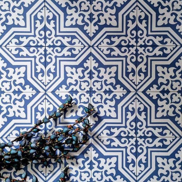 Draufsicht auf Berlin Trondite Feinsteinzeugfliesen im Format 20 × 20 cm im viktorianisch-marokkanisch inspirierten Stil, verlegt in einem sich wiederholenden Muster in Blau und Weiß. Ergänzt mit dekorativem Blattwerk, um das detailreiche, traditionell inspirierte Design hervorzuheben.