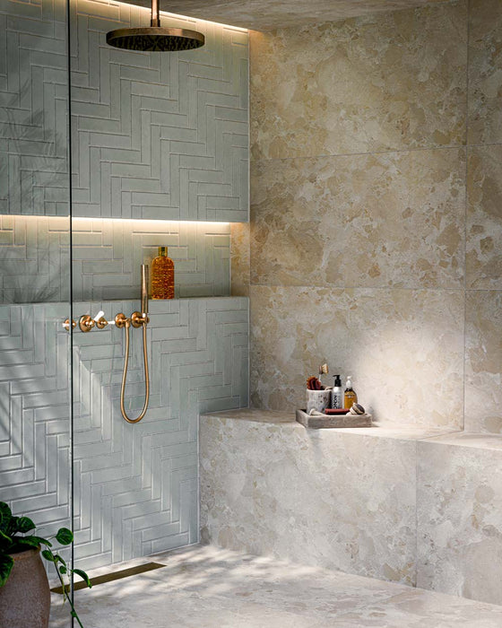 Badezimmer mit Nomadin Brick Mintgrün Wandfliesen im Industriestil im Format 6 × 24,6 cm, im Fischgrätmuster verlegt und mit glänzender Oberfläche in Mintgrün. Kombiniert mit Duscharmaturen in Messingoptik, eingelassenen Wandnischen und warmer indirekter Beleuchtung entsteht ein modernes und einladendes Badezimmerdesign.