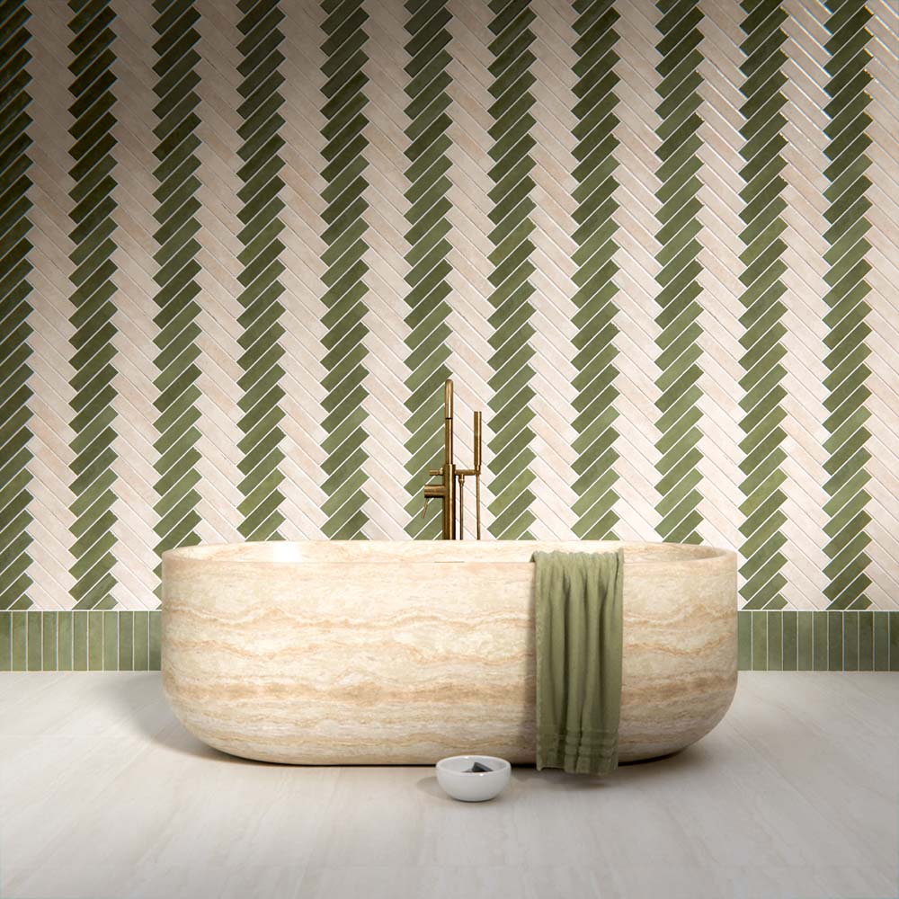 Modernes Badezimmer mit Nomadin Brick Creme Wandfliesen im Industriestil im Format 6 × 24,6 cm, im markanten Fischgrätmuster verlegt. Kombiniert mit salbeigrünen Akzenten, einer freistehenden Badewanne in Steinoptik und Armaturen in gebürsteter Messingoptik entsteht ein stilvolles und modernes Interior.
