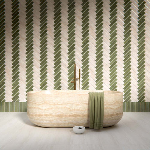 Modernes Badezimmer mit Nomadin Brick Creme Wandfliesen im Industriestil im Format 6 × 24,6 cm, im markanten Fischgrätmuster verlegt. Kombiniert mit salbeigrünen Akzenten, einer freistehenden Badewanne in Steinoptik und Armaturen in gebürsteter Messingoptik entsteht ein stilvolles und modernes Interior.