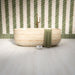 Modernes Badezimmer mit Nomadin Brick Creme Wandfliesen im Industriestil im Format 6 × 24,6 cm, im markanten Fischgrätmuster verlegt. Kombiniert mit salbeigrünen Akzenten, einer freistehenden Badewanne in Steinoptik und Armaturen in gebürsteter Messingoptik entsteht ein stilvolles und modernes Interior.