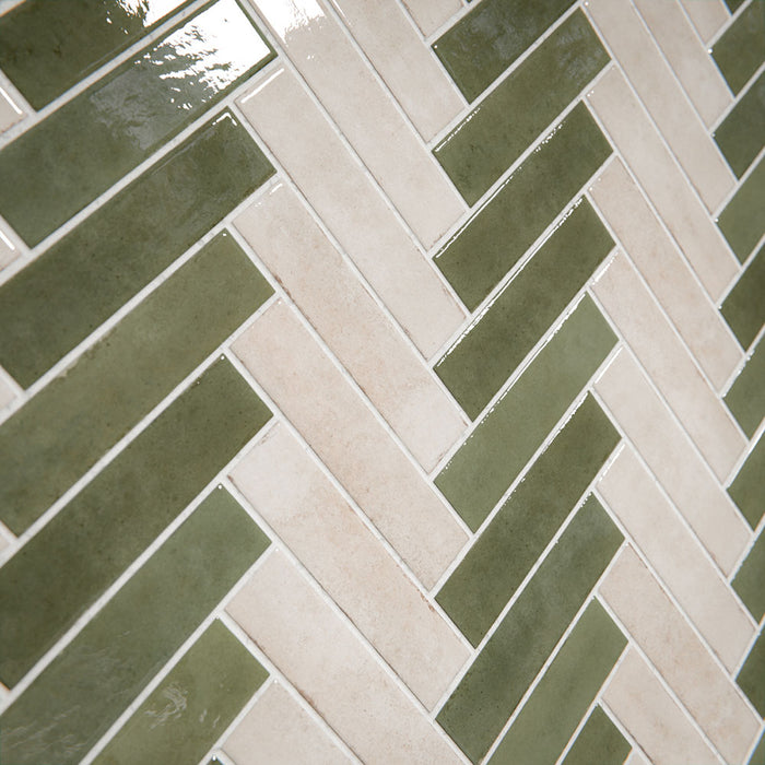Modernes Badezimmer mit Nomadin Brick Creme Wandfliesen im Industriestil im Format 6 × 24,6 cm, im markanten Fischgrätmuster verlegt. Kombiniert mit salbeigrünen Akzenten, einer freistehenden Badewanne in Steinoptik und Armaturen in gebürsteter Messingoptik entsteht ein stilvolles und modernes Interior.
