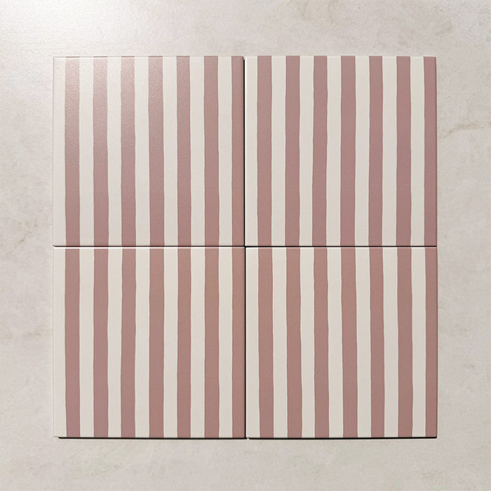 Produktpräsentation der Gestreift Rosa Dekorfliesen im Format 20 × 20 cm in sanften Blush- und Weißtönen, mit unregelmäßigen vertikalen Streifen in handgemalter Optik vor einem Hintergrund in dezenter Steinoptik.