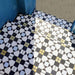 Nahaufnahme der Ravello 1 Bodenfliesen im Moroccan Style im Format 20 × 20 cm mit filigranem geometrischem Muster in Schwarz, Weiß, Grau und sanften Gelbtönen. Das dekorative Bodendesign schafft einen ausdrucksstarken Eingangsbereich und ist von traditioneller marokkanischer Handwerkskunst inspiriert.
