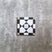 Produktabbildung der Ravello 1 Bodenfliese im Moroccan Style im Format 20 × 20 cm mit filigranem geometrischem Muster in Schwarz, Weiß, Grau, sanften Blautönen und gedecktem Gelb. Die Aufnahme zeigt das dekorative Design, das von traditioneller marokkanischer Handwerkskunst inspiriert ist.