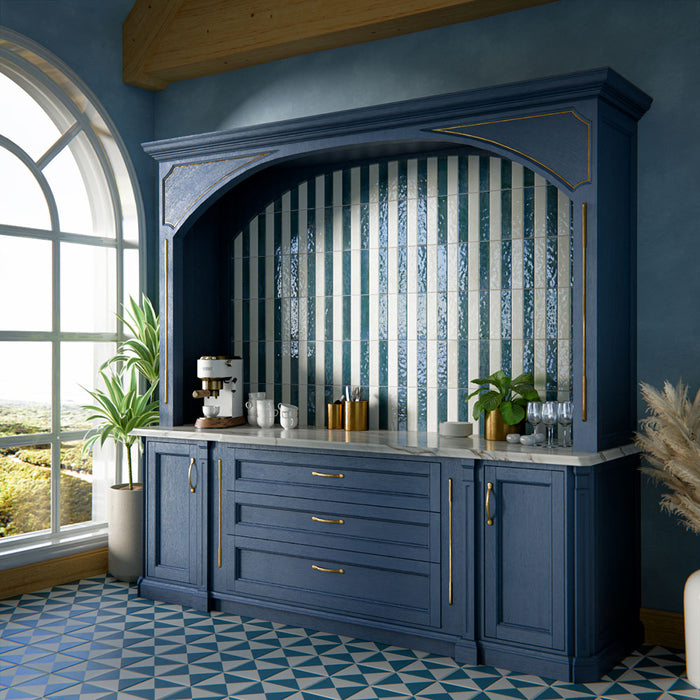 Kücheninterieur mit glänzenden Elazar Blue Ziegelfliesen im Format 6 × 25 cm, vertikal in einer Nische als Statement verlegt. Die satten Blautöne mit reflektierender Glasur sorgen für eine ausdrucksstarke Wirkung und werden durch tiefblaue Schränke, Messingakzente und eine Arbeitsplatte in Marmoroptik ergänzt – für ein zugleich markantes und elegantes Design.