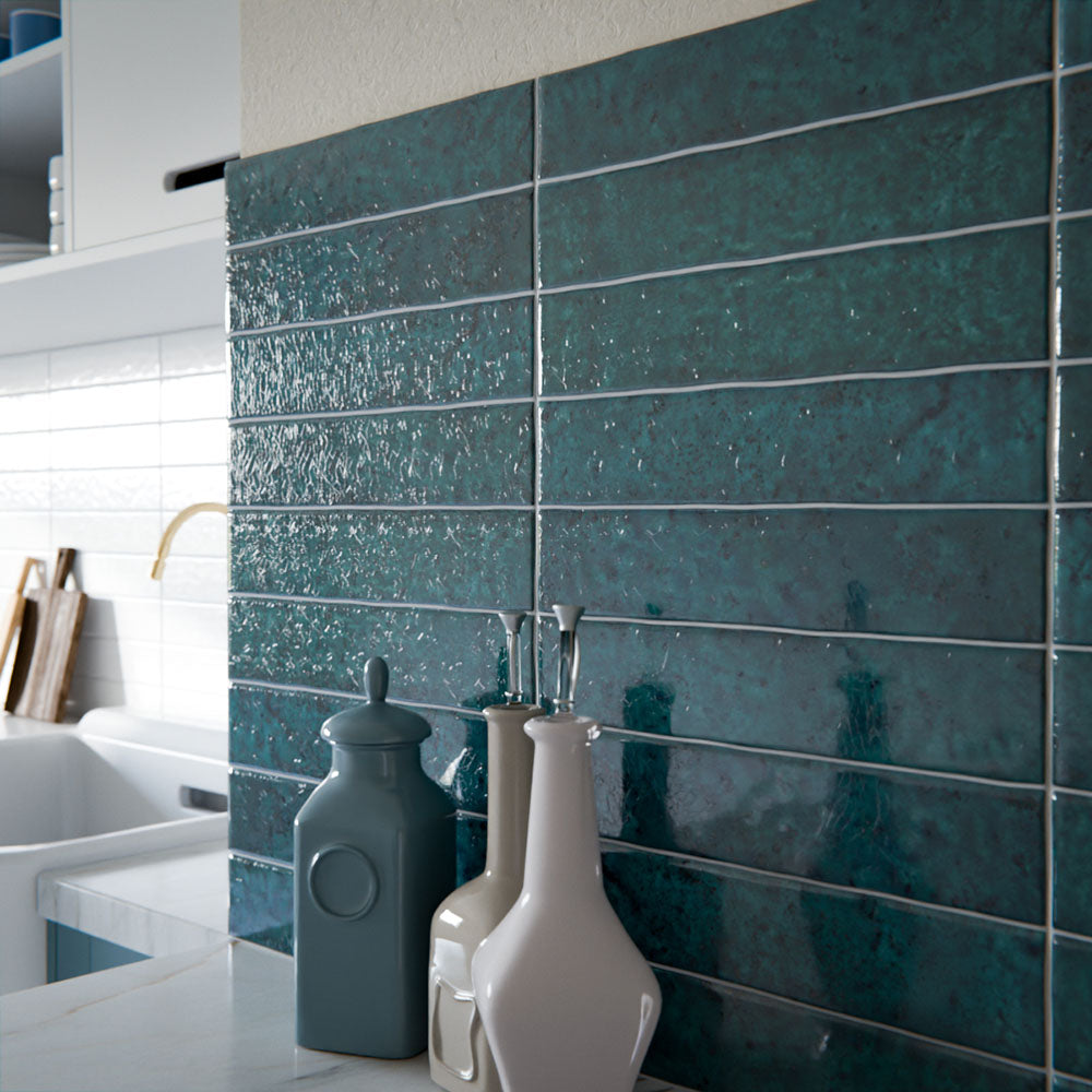 Küchenrückwand mit Bora Bora Ziegel Amun Blau Keramik-Wandfliesen im schlanken Riemchenformat 6,5 × 32,8 cm mit Fluxglasur, horizontal verlegt, um die satte Blau-Grün-Tonvariation zu betonen. In Kombination mit petrolfarbenen Schrankfronten, Arbeitsplatten in Marmoroptik und Armaturen in Messing entsteht ein ausdrucksstarker, zeitgemäßer Look.