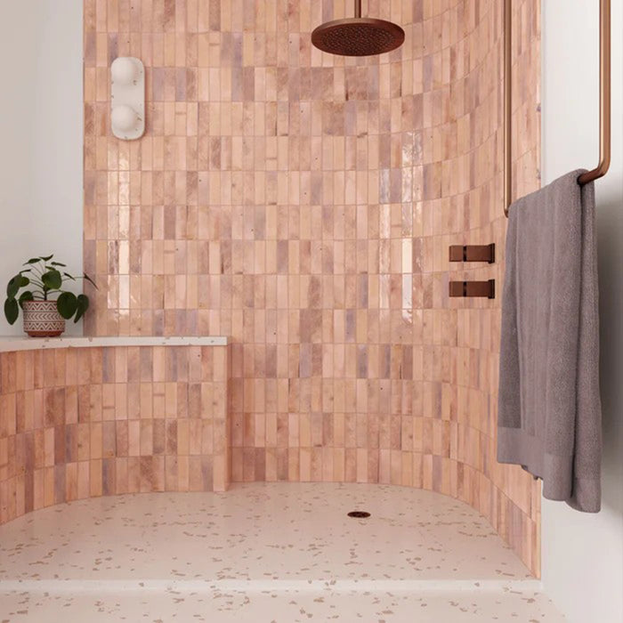 Duschbereich mit Saigon Rosa Brick Wandfliesen im marokkanisch inspirierten Stil. Glänzende Keramikfliesen im Format 5,1 × 16,1 cm in sanften Blush- und Rosétönen, kombiniert mit Duscharmaturen in Kupfer.