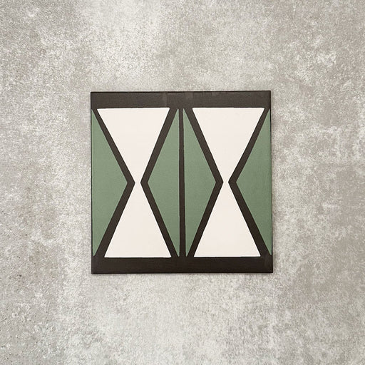 Einzelne Abstrakte Sanduhr Musterfliese im Format 20 × 20 cm mit einem markanten geometrischen Sanduhrdesign in gedecktem Grün und sanftem Creme, akzentuiert durch anthrazitfarbene Details. Eine moderne Musterfliese, ideal für Akzentwände, Bodenflächen oder ausdrucksstarke Küchenrückwände.