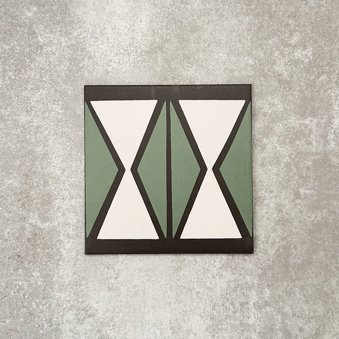 Einzelne Abstrakte Sanduhr Musterfliese im Format 20 × 20 cm mit einem markanten geometrischen Sanduhrdesign in gedecktem Grün und sanftem Creme, akzentuiert durch anthrazitfarbene Details. Eine moderne Musterfliese, ideal für Akzentwände, Bodenflächen oder ausdrucksstarke Küchenrückwände.
