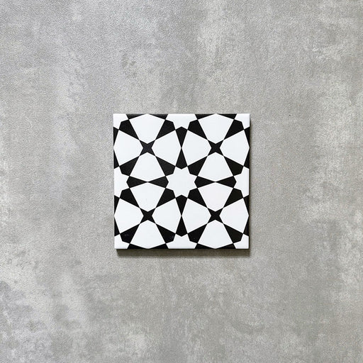 Einzelne Agadir MINI Schwarz & Weiß Fliese im marokkanischen Stil im Format 15 × 15 cm aus Feinsteinzeug mit markantem geometrischem Sternmuster in Schwarz und Weiß, dargestellt auf neutralem Hintergrund.