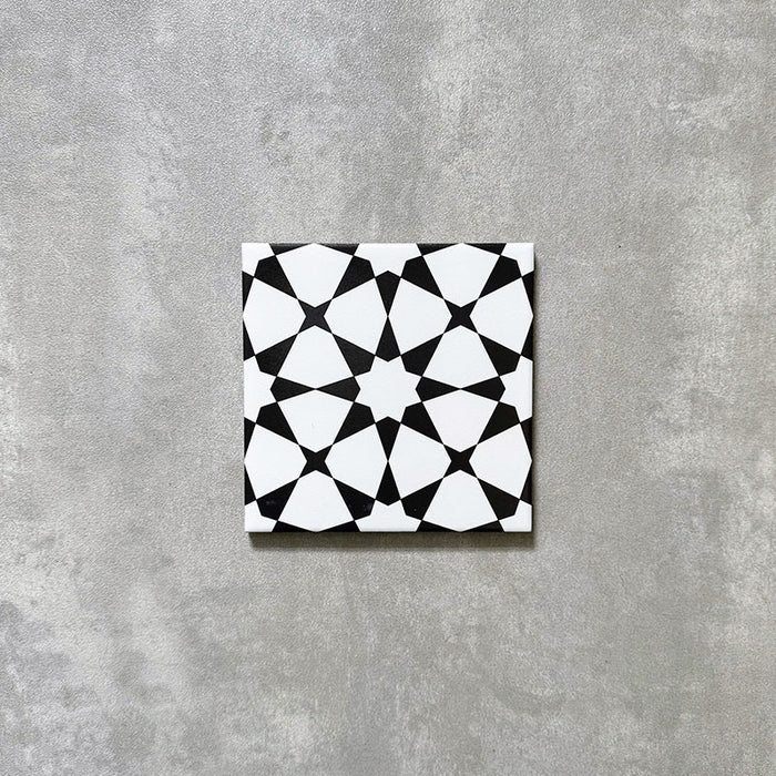 Einzelne Agadir MINI Schwarz & Weiß Fliese im marokkanischen Stil im Format 15 × 15 cm aus Feinsteinzeug mit markantem geometrischem Sternmuster in Schwarz und Weiß, dargestellt auf neutralem Hintergrund.