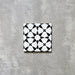 Einzelne Agadir MINI Schwarz & Weiß Fliese im marokkanischen Stil im Format 15 × 15 cm aus Feinsteinzeug mit markantem geometrischem Sternmuster in Schwarz und Weiß, dargestellt auf neutralem Hintergrund.