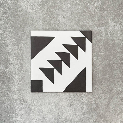 Einzelne Almeira Azteca Feinsteinzeugfliese im marokkanischen Stil mit einem markanten geometrischen Dreiecksmuster in Schwarz und Weiß, einzeln dargestellt auf neutralem Hintergrund, Format 20 × 20 cm.