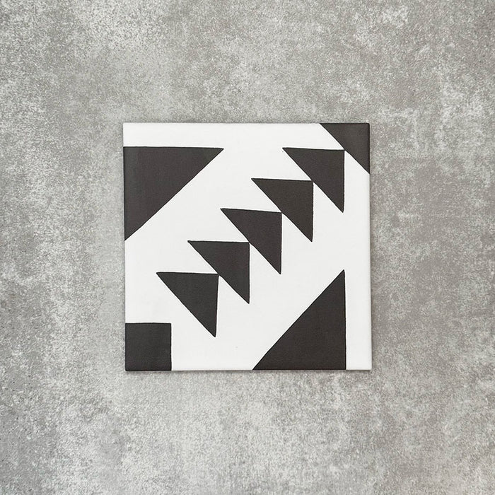 Einzelne Almeira Azteca Feinsteinzeugfliese im marokkanischen Stil mit einem markanten geometrischen Dreiecksmuster in Schwarz und Weiß, einzeln dargestellt auf neutralem Hintergrund, Format 20 × 20 cm.