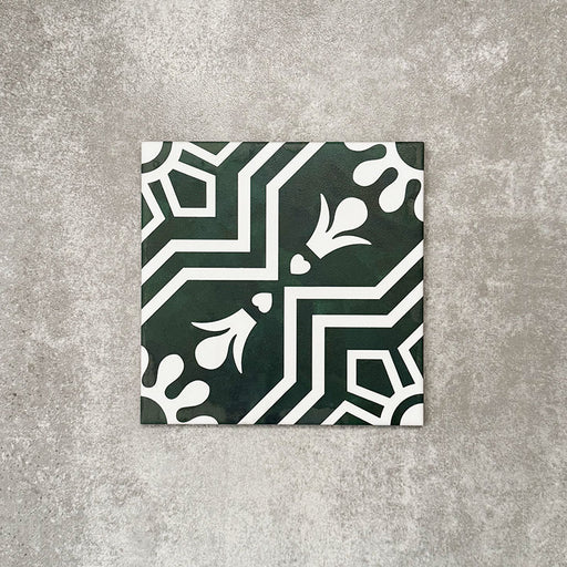 Einzelne Berlin Grün Keramikfliese im Format 20 × 20 cm im viktorianisch inspirierten Stil in Grün und Weiß mit markantem geometrischem und floralem Motiv, inspiriert von marokkanischem Design, präsentiert vor einem neutralen, strukturierten Hintergrund.