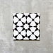 Einzelne Agadir Schwarz & Weiß Fliese im marokkanischen Stil im Format 20 × 20 cm aus Feinsteinzeug mit einem markanten geometrischen Sternmuster in Schwarz und Weiß, dargestellt auf neutralem Hintergrund.