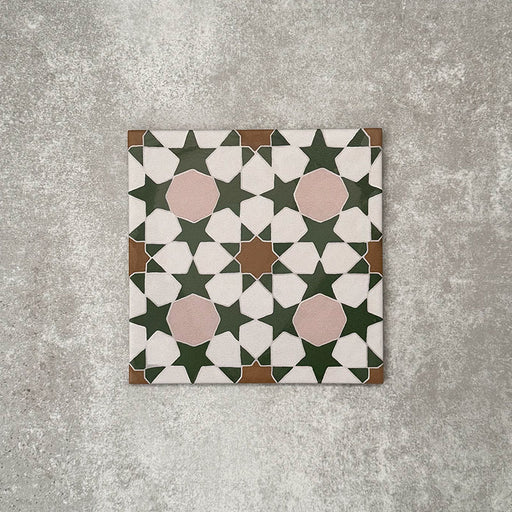 Einzelne Kuba Tanane Feinsteinzeugfliese im marokkanischen Stil im Format 20 × 20 cm, mit einem wiederkehrenden geometrischen Sternmuster in tiefem Grün und Weiß, ergänzt durch zarte Rosé-Akzente und warme Brauntöne, gezeigt vor neutralem Hintergrund.
