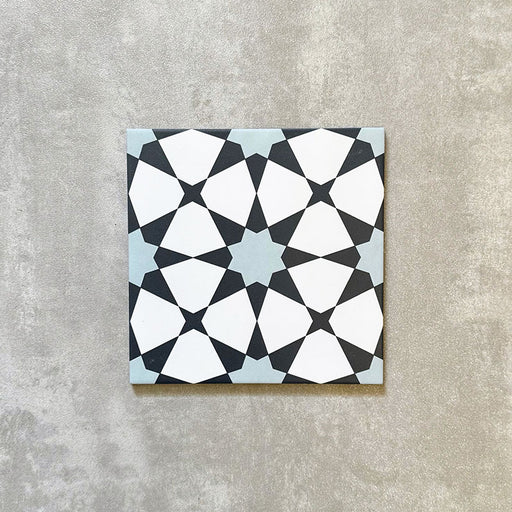 Einzelne Agadir Blau Fliese im marokkanischen Stil im Format 20 × 20 cm aus Feinsteinzeug mit geometrischem Sternmuster in Blau, Schwarz und Weiß, dargestellt auf neutralem Hintergrund.