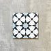 Einzelne Agadir Blau Fliese im marokkanischen Stil im Format 20 × 20 cm aus Feinsteinzeug mit geometrischem Sternmuster in Blau, Schwarz und Weiß, dargestellt auf neutralem Hintergrund.