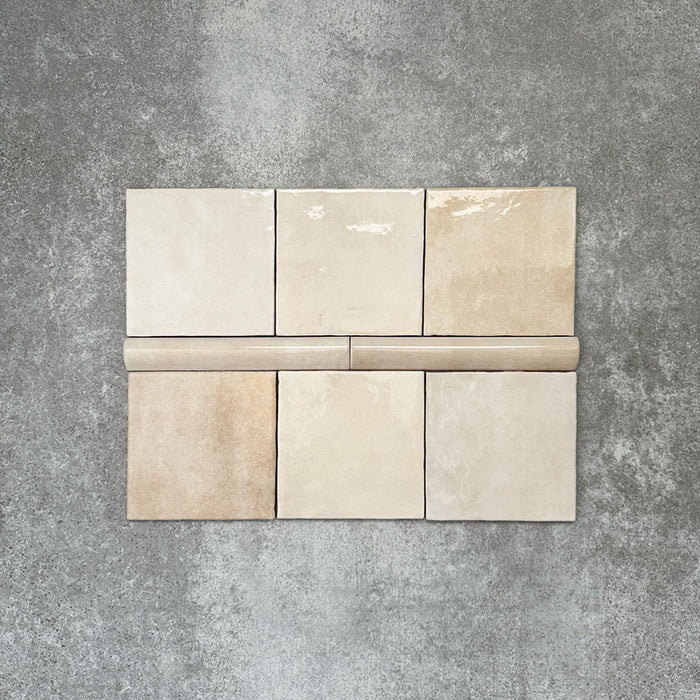 Zellige Beige Bullnose-Keramikfliesen in sanftem Beigeton, kombiniert mit passenden Quadratfliesen, als Flatlay angeordnet.