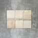 Zellige Beige Bullnose-Keramikfliesen in sanftem Beigeton, kombiniert mit passenden Quadratfliesen, als Flatlay angeordnet.