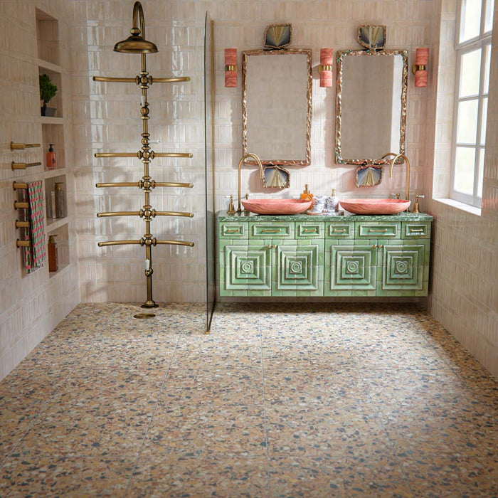 Luxury bathroom featuring Stuzzi Amber 60x60cm classical terrazzo style porcelain floor tiles with a 4D brushed finish, paired with soft blush gloss wall tiles, a sage green vanity unit, pink basins, brushed brass fittings and vintage-inspired details.