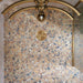 Luxury bathroom featuring Stuzzi Amber 60x60cm classical terrazzo style porcelain floor tiles with a 4D brushed finish, paired with soft blush gloss wall tiles, a sage green vanity unit, pink basins, brushed brass fittings and vintage-inspired details.