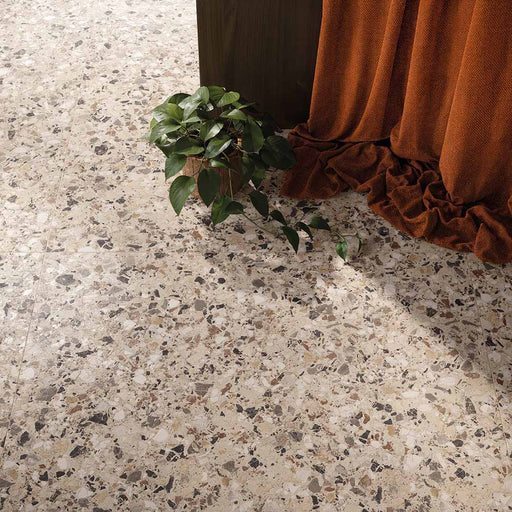 Overhead view of the Stuzzi Dolmia 60x120cm terrazzo style porcelain floor tiles, featuring a warm beige base with a blend of cream, taupe, brown, grey and charcoal stone fragments. The realistic 4D brushed finish adds texture and depth, creating a timeless terrazzo effect in a contemporary interior.