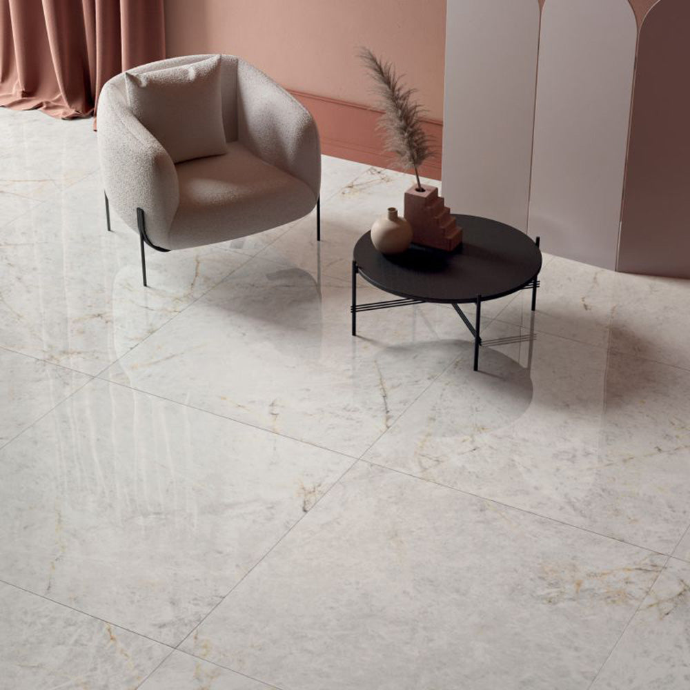 Living space featuring Taj Mahal Matt 60 × 60cm marble effect porcelain wall and floor tiles, showcasing soft cream tones with delicate, flowing veining. The matt finish creates a calm, refined surface, complemented by warm, tonal furnishings and a softly styled interior.