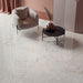 Living space featuring Taj Mahal Matt 60 × 60cm marble effect porcelain wall and floor tiles, showcasing soft cream tones with delicate, flowing veining. The matt finish creates a calm, refined surface, complemented by warm, tonal furnishings and a softly styled interior.