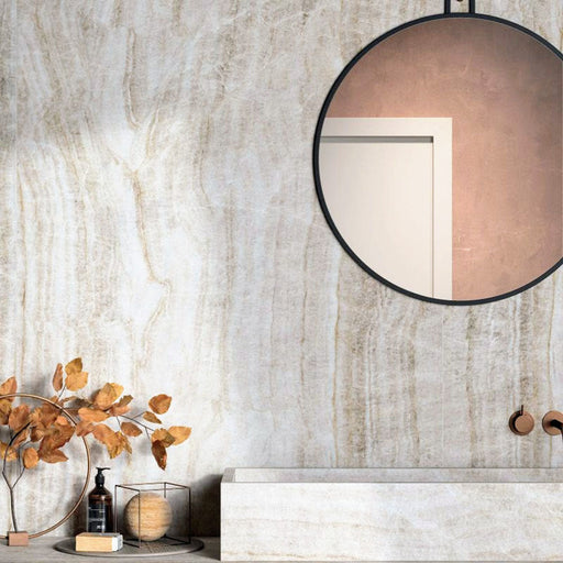 Bathroom interior featuring Taj Mahal Polished Marble effect 60 × 120cm porcelain wall tiles, styled with a floating vanity, round mirror, warm brass fittings, and autumnal decor highlighting soft beige tones and natural veining.