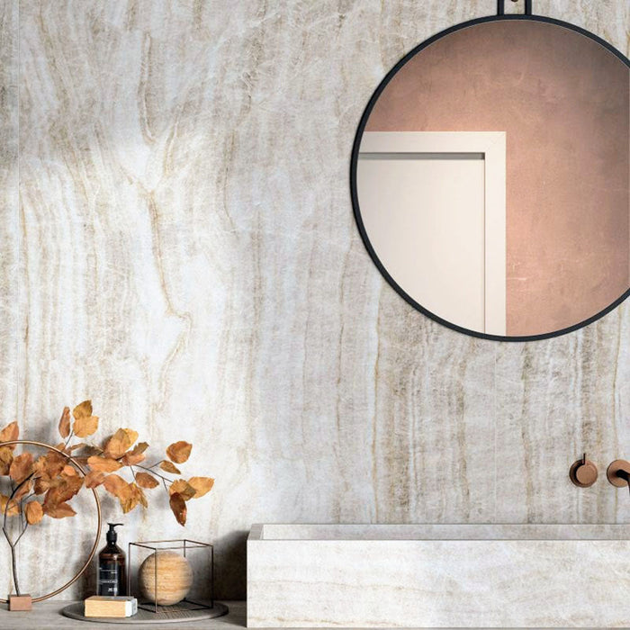 Bathroom interior featuring Taj Mahal Polished Marble effect 60 × 120cm porcelain wall tiles, styled with a floating vanity, round mirror, warm brass fittings, and autumnal decor highlighting soft beige tones and natural veining.