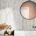 Bathroom interior featuring Taj Mahal Polished Marble effect 60 × 120cm porcelain wall tiles, styled with a floating vanity, round mirror, warm brass fittings, and autumnal decor highlighting soft beige tones and natural veining.