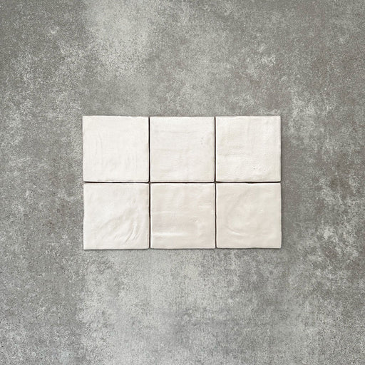 Flatlay mit Zellige Auster Quadrat Keramikfliesen im marokkanischen Stil im Format 10 × 10 cm, das die sanft unregelmäßigen Kanten, feine Oberflächenwellen und die dezente tonale Variation hervorhebt, die den handgefertigten Charakter der glänzenden Auster-Glasur unterstreichen.
