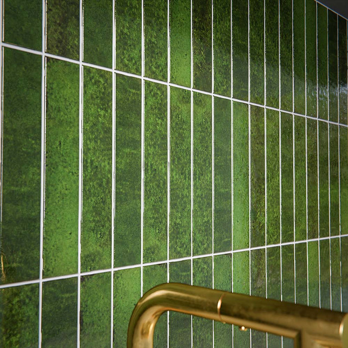 Moderne Küchenrückwand mit Bora Bora Brick Tourmaline Green Wandfliesen im Format 6,5 × 32,8 cm, kombiniert mit dunklen Küchenfronten, einer Arbeitsplatte in Marmoroptik und Armaturen in gebürsteter Messingoptik für eine luxuriöse Ausstrahlung.