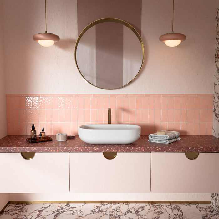 Großartig Violetta Matt Wand- und Bodenfliesen aus Feinsteinzeug im Format 60 × 60 cm in Marmoroptik, mit markanter Maserung in Rosa, Burgunderrot und Grau auf dem Badezimmerboden, kombiniert mit rosafarbenen Wandfliesen, einer Arbeitsplatte in Terrazzo-Optik und warmen Messingdetails.
