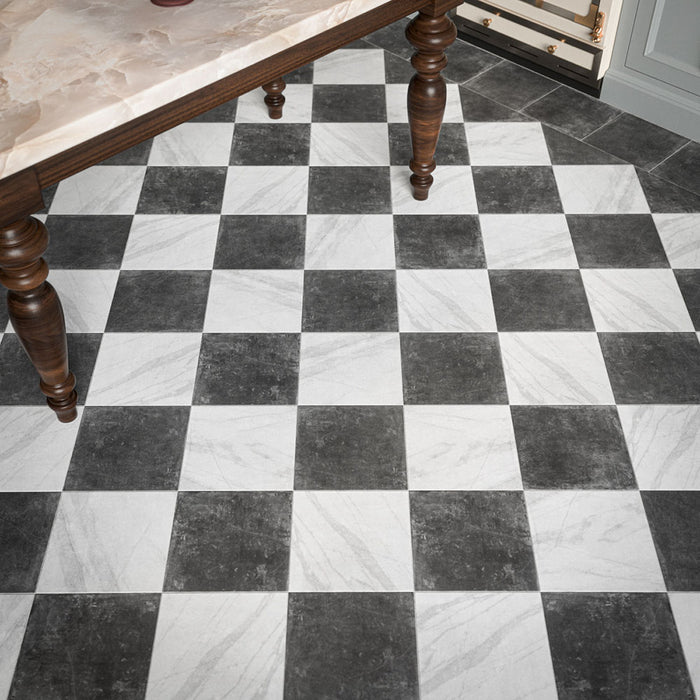 Vitoria Antique Weiß Schachbrettfliesen im Format 30 × 30 cm in Marmoroptik, die auf dem Küchenboden ein klassisches schwarz-weißes Schachbrettmuster bilden, eingerahmt von einer dunklen Bordüre und kombiniert mit einer Marmor-Kücheninsel.