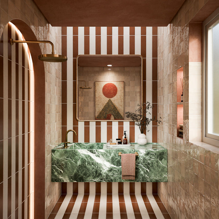 Badezimmer mit Zellige Beige Quadrat 13,2cm x 13,2cm Wandfliesen im marokkanischen Stil, kombiniert mit gestreiften Bodenfliesen, grünem Marmorwaschtisch, Messingarmaturen und warmen Terrakottatönen.